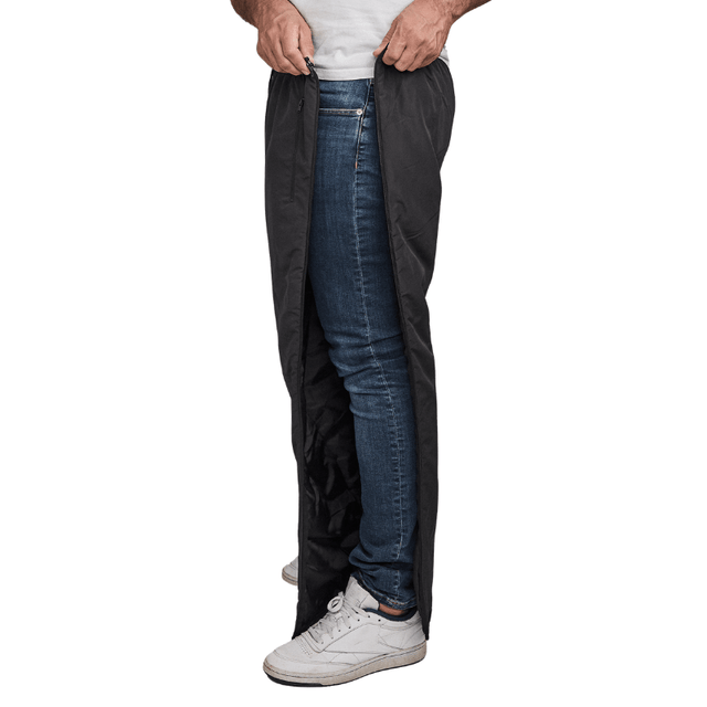 Mann åpner svarte Dobsom termobukser i siden, over blå jeans og hvite joggesko